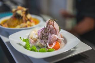 Table dressée dans une salle de restaurant, carte ouverte devant une assiette de crudités