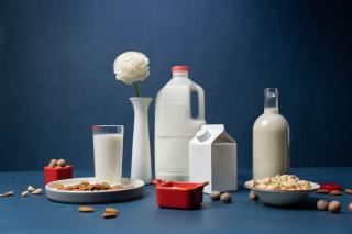 Bouteilles et bols de boissons végétales à l'amande et à l'avoine sur une table en bois